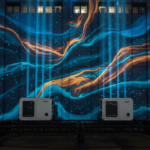 Hong Kong tower covered by abstract projection mapping artwork with laser projectors on a truss in the foreground